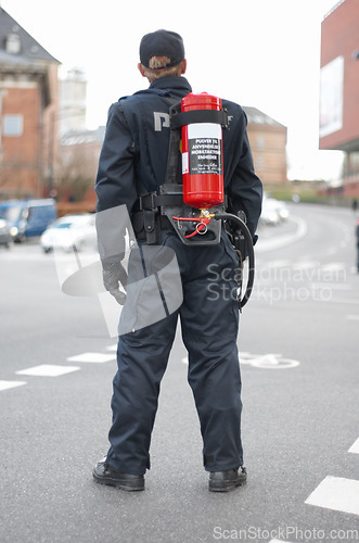 Image of Emergency, police and man safety officer or fireman working a neighborhood street feeling fearless and ready for service. Security, legal and rearview of law enforcement person in a urban town