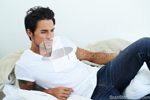 Image of Fashion, relax or casual with a sexy man in studio wearing jeans and a t-shirt while lying on the floor. Idea, lifestyle and natural with a handsome young male model thinking while relaxing at home