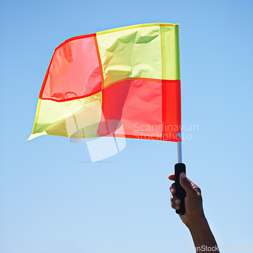 Image of Flag, stop and soccer referee in football match or game wave a foul sign during sport training or workout. Hand, sports and person or assistant official raise or signal mistake in sky background