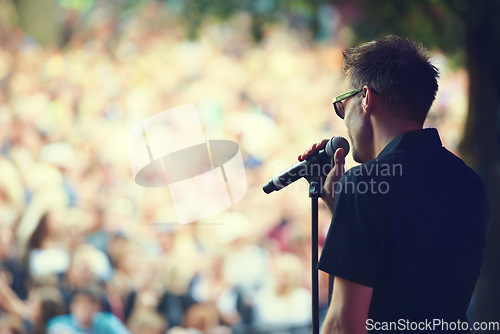 Image of Music, microphone and concert with man at festival for rock, performance and party in nature. Celebration, energy and audience with male singer on stage for club, rave and dj event in outdoors