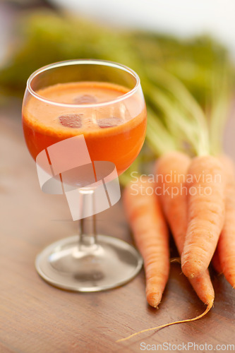 Image of Vegetable, carrot juice and healthy food with color, art and creativity for nutritionist menu. Vegan smoothie drink in glass for wellness, diet or nutrition on a wooden table with ingredients