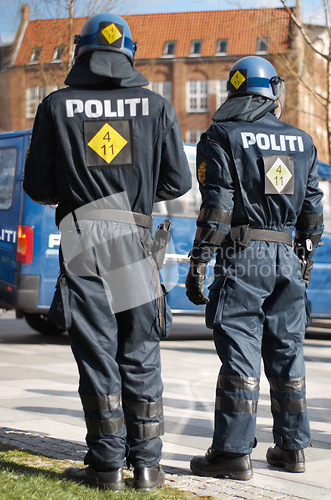 Image of Security, riot and protest with police officer in city for law enforcement, protection or safety. Brave, uniform and government with people in street for demonstration rally, human rights or control