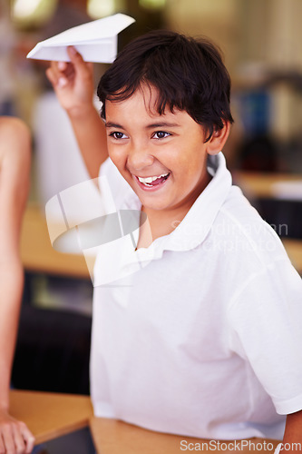 Image of School, classroom and a boy playing with a paper airplane while learning for education or child development. Study, children and growth with a male student having fun in an elementary class for kids