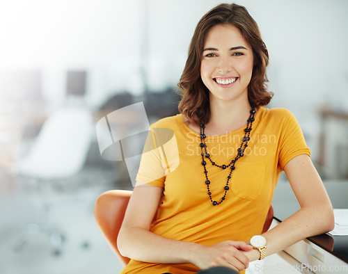 Image of Portrait, smile and a business woman in the office, sitting at her desk feeling positive about her career. Happy, professional and confidence with a young female employee looking cheerful at work