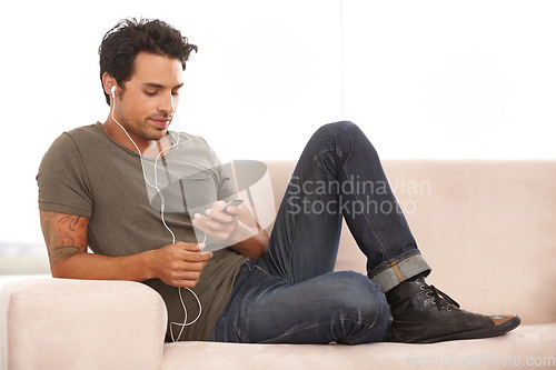 Image of Relax, technology and a man with music on the sofa, streaming and calm in a house. Happy, home and a person on the living room couch listening to a podcast, audio or radio on digital tech online