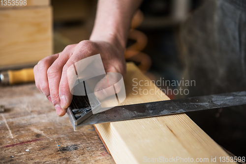 Image of The worker makes measurements of a wooden board