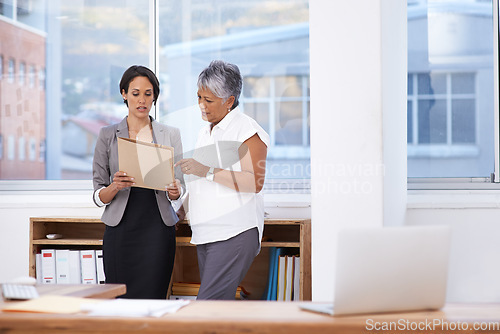 Image of Business women, paperwork and talking in office for planning, brainstorming or advice. Corporate team or manager and employee together for discussion, collaboration or teamwork on a report or project