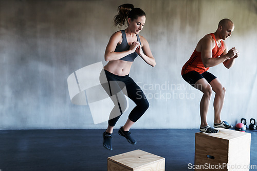 Image of Gym, fitness and people on jump box for training, cardio or workout routine on wall background. Jumping, exercise and woman with personal trainer for endurance, challenge or leg strength performance