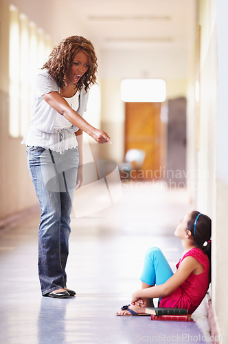 Image of School, teacher and shouting at child student for bad behaviour, problem or lesson. Angry black woman pointing and scolding girl for discipline, attitude or education fail in building hallway