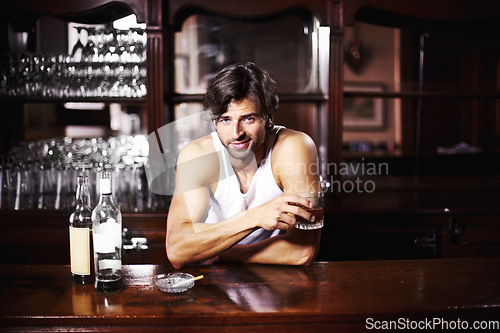 Image of Portrait, whisky and alcohol with a handsome barman behind the counter of a pub to serve drinks during happy hour. Sexy, glass and drink with a man bartender drinking a whiskey beverage in a bar