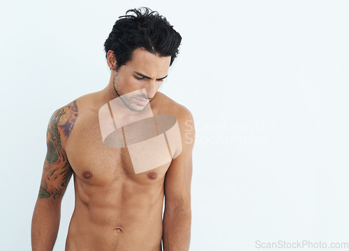 Image of Shirtless, fitness and man standing and thinking isolated on a white background for health, wellness or body depression. Sad, training and thoughtful model or person with abs and tattoo in studio