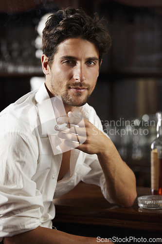 Image of Portrait, young man and smoking at a bar or cigarette at hand or handsome guy relaxing and unbuttoned shirt. Sexy, masculine and attractive model with ash tray or about to have a drink after work