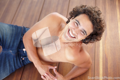 Image of Portrait, fit and shirtless man in jeans laying down on wood floor with happy and sexy smile. Attractive, healthy and topless guy laughing with sensual skin, body and bare chest in Mexico at home