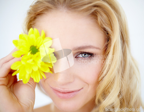 Image of Beauty, portrait and woman with a flower in a studio with a cosmetic, natural and face routine. Happy, smile and young female model with a yellow floral plant for facial isolated by white background.