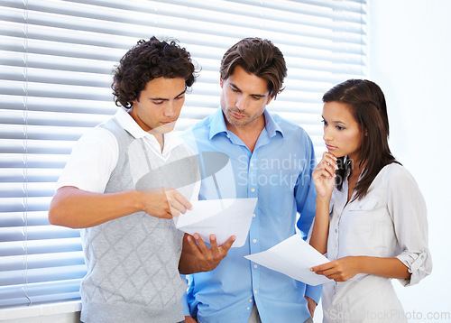 Image of Business people, documents and planning in meeting for teamwork, strategy or serious brainstorming at office. Group of concerned employees working on paperwork, problem solving or tasks at workplace