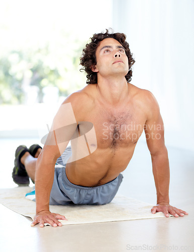 Image of Yoga, man and cobra stretch in home for health, wellness and flexibility in house. Pilates, stretching and male person, yogi or athlete training, holistic workout and exercising for fitness on mat.