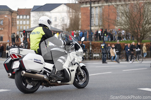 Image of Emergency, motorbike and police or safety officer working for protection and peace in an urban town in Denmark. Security, law and legal professional or policeman on a motorcycle ready for service