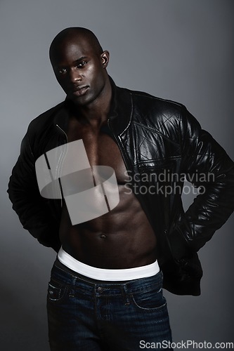 Image of Portrait, muscle and black man in leather jacket in studio isolated on a gray background. Serious, African male model and abs, stylish fashion clothes and trendy jeans with confidence from Nigeria.