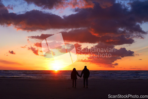 Image of Silhouette, couple holding hands at sunset and on beach walking together. Love or care, holiday or vacation and shadows of people on the seashore for embrace for romance date or honeymoon outdoor