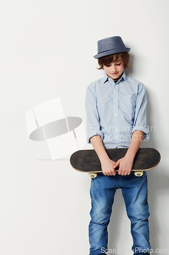 Image of Skateboard, young boy with a hat and mockup in studio background with space. Trendy fashion or casual wear, confident or cool and isolated person posing for clothing advertisement in backdrop