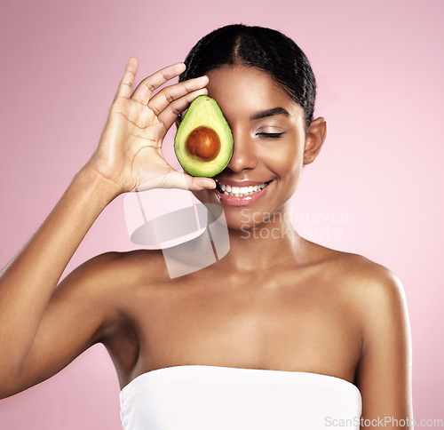 Image of Avocado, happy woman and healthy beauty in studio, pink background and aesthetic glow. African model, natural skincare and organic cosmetics for sustainability, vegan dermatology and facial nutrition