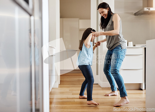 Image of Holding hands, dance and a child with a mother in the kitchen, bonding and quality time together. Smile, laughing and a mom teaching her daughter with dancing, love and happiness with fun in a house