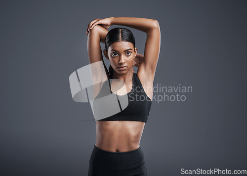 Image of Portrait, mockup and stretching with a sports woman in studio on a gray background for fitness or health. Exercise, workout and warm up with an attractive young female athlete training her body
