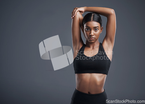 Image of Portrait, mock up and stretching with an athlete woman in studio on a gray background for fitness or health. Exercise, workout or getting ready with an attractive young female model training her body