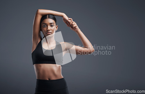 Image of Portrait, mockup space and warm up with an athlete woman in studio on a gray background for exercise or health. Fitness, workout and stretch with an attractive young female model training her body