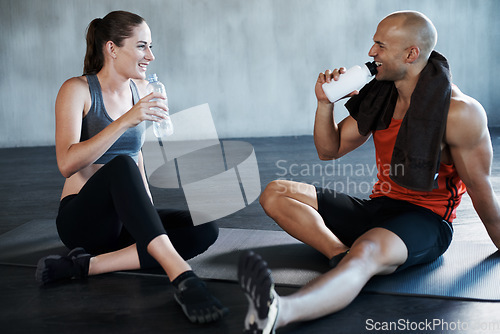 Image of Fitness, friends and relax on a gym floor for water, break and talking after cardio or routine. Active, people and woman with personal trainer relaxing after training, workout or physical exercise