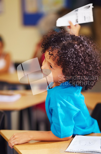 Image of School, education and paper airplane with a student boy playing in class while sitting at his desk. Classroom, study and learning with an adhd pupil feeling bored while studying for child development