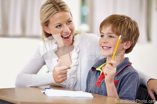 Image of Thumbs up, happy teacher with student in classroom in school and teaching. Correct or success, education or learning and female educator helping male child with homework or question at desk.