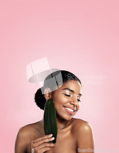 Image of Happy woman, skincare and natural leaf in studio, pink background and space for eco friendly cosmetics. Face, african model and beauty from green plants, leaves and sustainability of vegan aesthetic