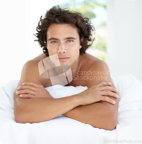 Image of Portrait, relax and man on a bed, freedom and chilling at home, weekend break and morning. Face, male person and model with wellness, carefree and health in a room, apartment and wake up with peace