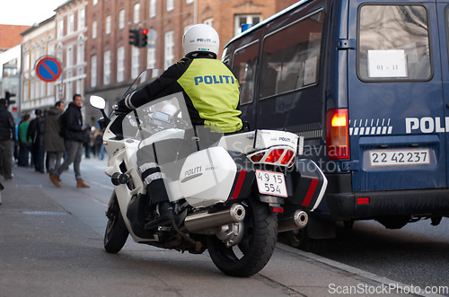 Image of Emergency, motorbike and city safety police officer working for protection and peace in an urban town in Denmark. Security, law and legal professional or policeman on a motorcycle ready for service