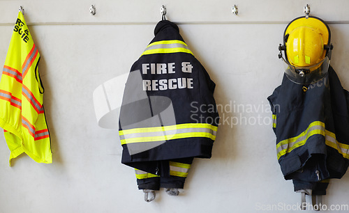 Image of Fireman, uniform and clothing hanging on wall rack at station for fire fighting protection. Firefighter gear, rescue jacket and helmet with reflector for emergency services, equipment or department