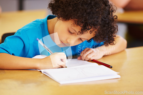 Image of Boy, writing and book in school classroom for learning, focus or development for future. Male child, pen and paper for studying, education and test for thinking, scholarship or concentration in class