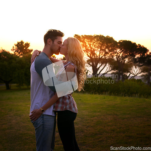 Image of Couple kiss, nature and trees in sunset with love, romance and date on adventure, travel or honeymoon. Man, woman and kissing with hug, care and outdoor for safari, freedom or holiday in countryside