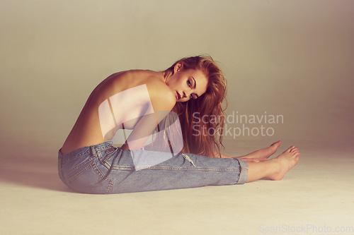 Image of Portrait, fashion and topless woman in jeans sitting on floor with long hair, designer clothes and studio background. Art, aesthetic beauty and model with luxury makeup, mockup sexy retro denim style