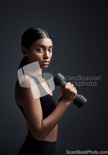 Image of Portrait, serious and woman with dumbbell for workout in studio isolated on a black background. Strong, bodybuilder and Indian female athlete weightlifting for muscle, training and fitness exercise.