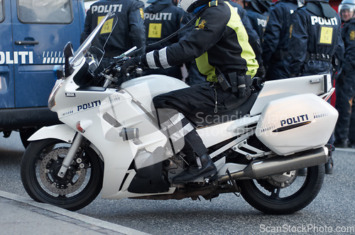 Image of Emergency, road and motorcycle police officer working for protection and peace in an urban town in Denmark. Security, traffic and legal professional or policeman on a motorbike ready for service