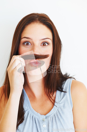 Image of Comic, portrait and a woman with hair moustache isolated on a white background in studio. Smile, funny and a young girl being crazy, making face and playing with hairstyle for comedy on a backdrop