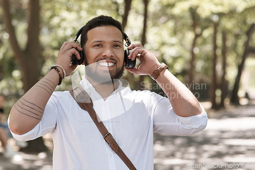 Image of Happy, portrait and a businessman with music in a park to travel to work in the morning. Smile, young and a male corporate employee listening to a podcast, streaming the radio or audio in nature
