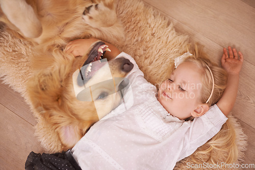 Image of Girl, dog and hug together on floor in living room and golden retriever, kid and relaxing with pet on lounge carpet. Young child, Labrador and bonding in family home, pets and dogs with children