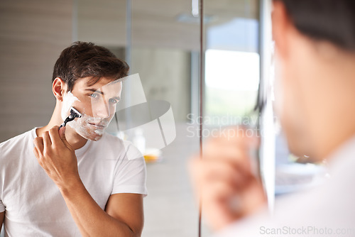 Image of Mirror, shaving and face of man in bathroom for facial grooming, wellness and skincare at home. Health, skincare and serious male person shave beard for hygiene, cleaning and hair removal with razor