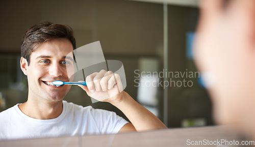 Image of Brushing teeth, man and cleaning in a bathroom at home for oral hygiene and health. Smile, dental and toothbrush with a male person with happiness in the morning at a house with mirror reflection