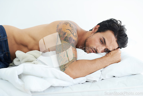 Image of Sad, young man in bed and depressed in bedroom in white background. Sleeping for mental health, insomnia and shirtless male person resting for peace or comfort on mattress in studio backdrop