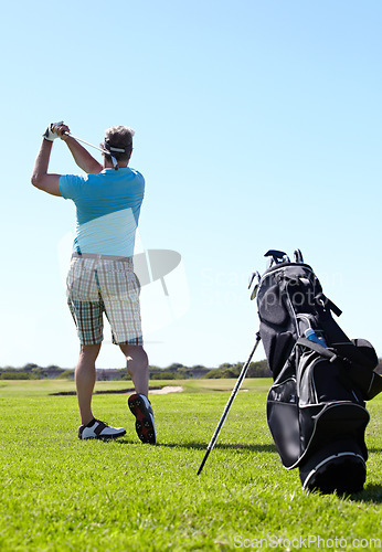 Image of Swing, golf and behind man with driver on a field for training, hobby and sports on blue sky background. Club, swinging and rear view of male golfer on field for fitness, match or sports practice