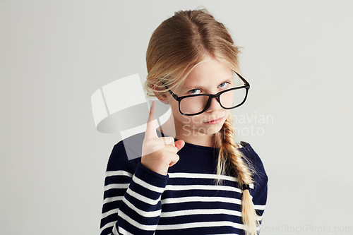 Image of Strict, serious and portrait of a child with a gesture isolated on a white background in a studio. Rude, smart and a young girl wearing glasses and gesturing with finger for discipline on a backdrop