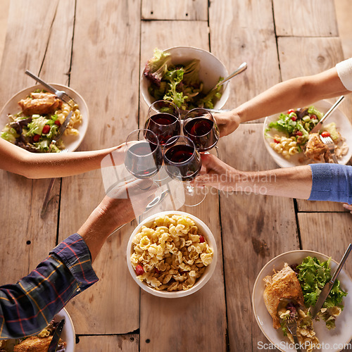 Image of Hands, toast with wine glasses and food with cheer for celebration at lunch. Top view of event, congratulations or success and friends or family sharing a meal or dish together at table with drinks